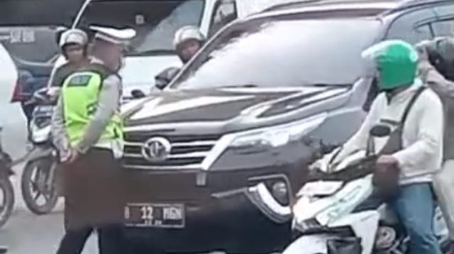 Seorang pengemudi mobil Pajero ngegas mau menerobos anggota Polantas yang memberhentikannya di simpang Cengkareng, Jakarta Barat pada Senin (20/3).